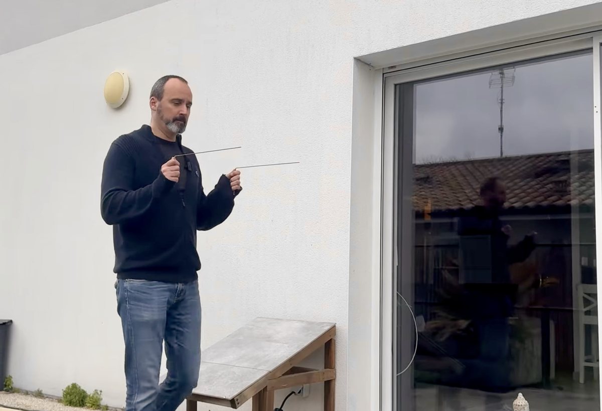 Sébastien Gossart pratiquant la radiesthésie avec ses baguettes L en extérieur